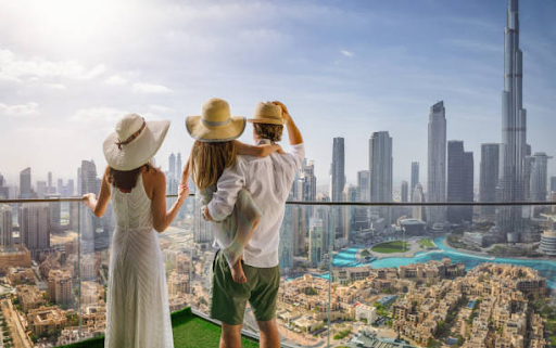 Three people enjoying a panoramic city skyline view from a high-rise balcony, symbolizing the luxury of Elo 3 at DAMAC Hills 2.